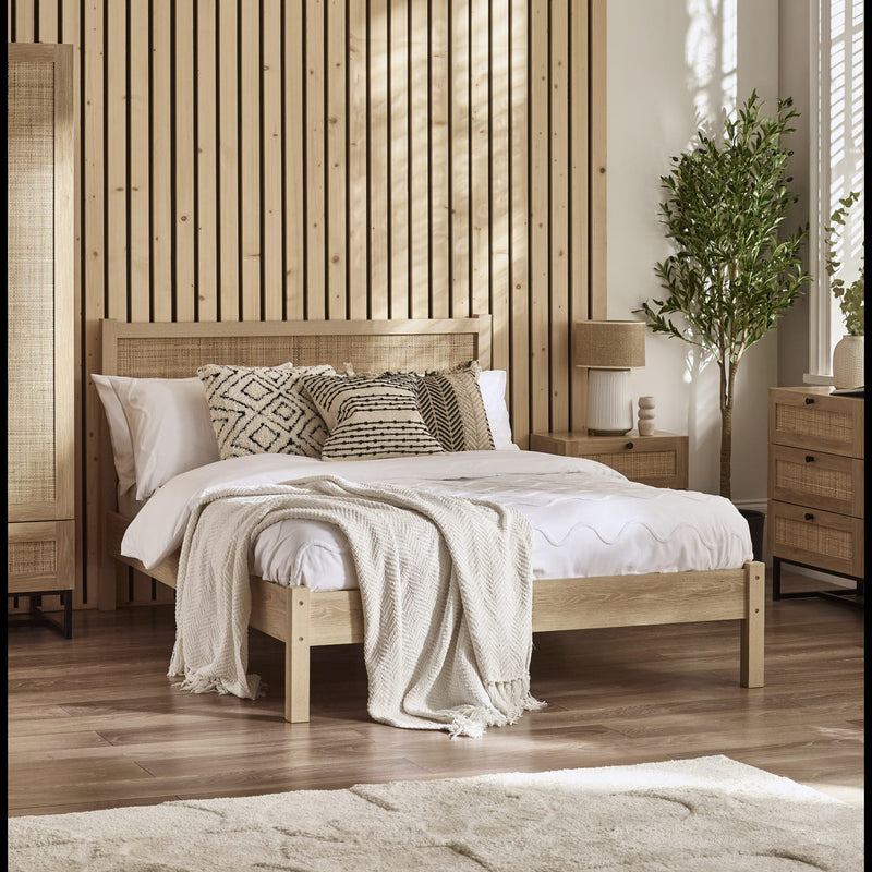 Bedroom with wooden bed, pillows, and a plant in a well-lit room.