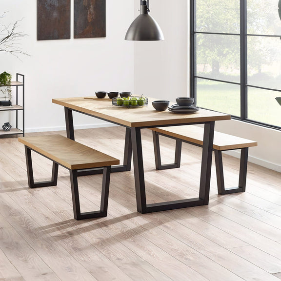 Dining table with benches in a modern room with large windows.