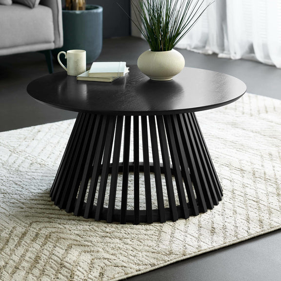 Black coffee table with a vase and books in a living room setting