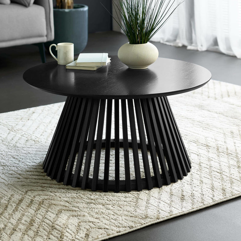 Black coffee table with a vase and books in a living room setting