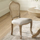 Wooden chair with wicker backrest in a room with a table and rug.