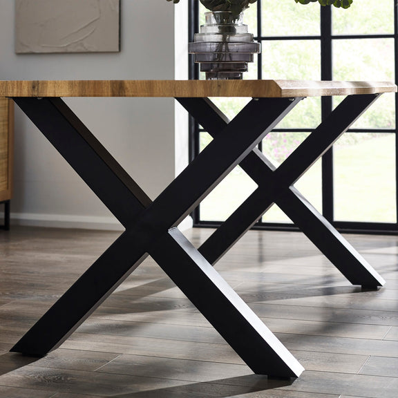 Dining table with black X-shaped legs in a room with large windows.