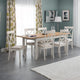 Dining room with a wooden table and white chairs against a gray wall.