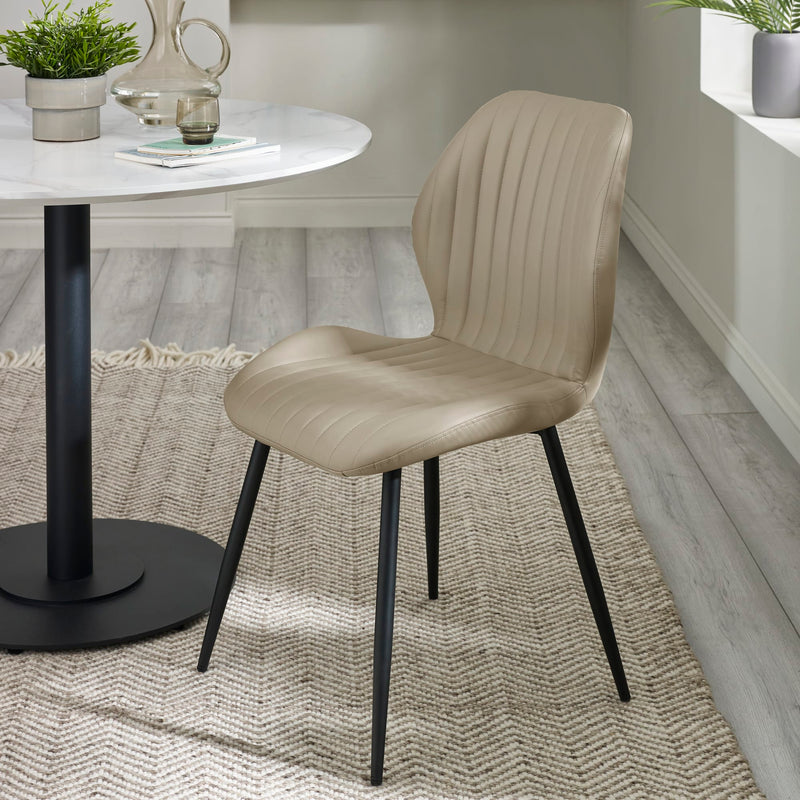 Beige chair with black legs in a room with a round table and decor items.