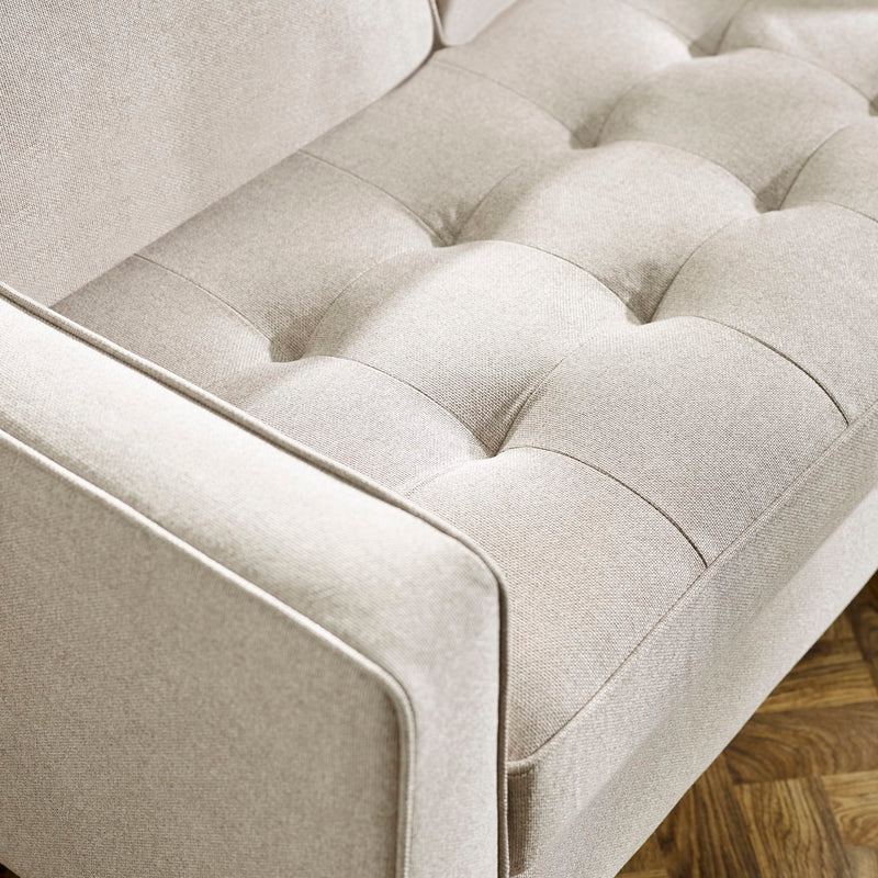 Close-up of a beige tufted sofa with wooden floor in the background