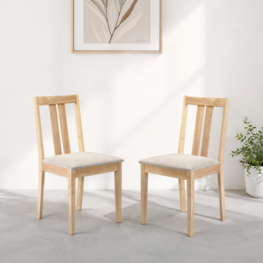 Two wooden chairs with beige cushions in a room with a plant and framed picture on the wall.