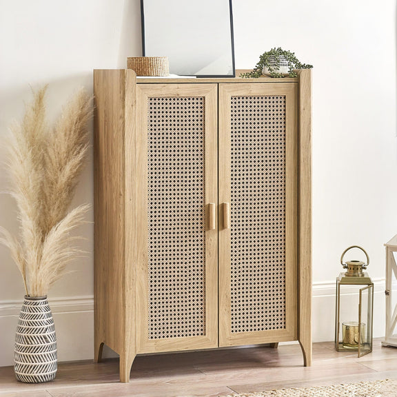 Wooden cabinet with rattan doors in a room setting with decor items.