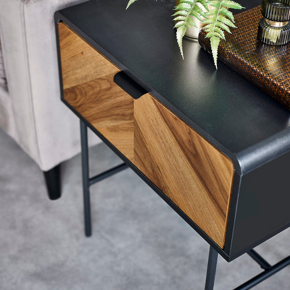 Modern side table with black top and wooden sides on a gray floor.