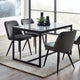 Dining table with four chairs in a modern room with large windows.
