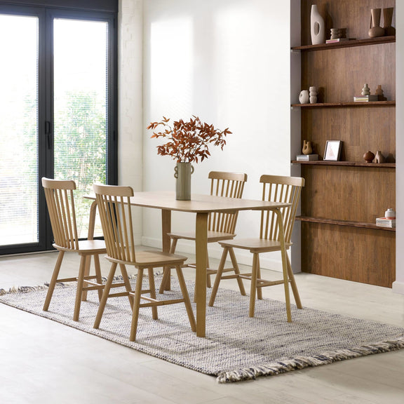 Dining room with wooden table and chairs, rug, and shelves with decor items.
