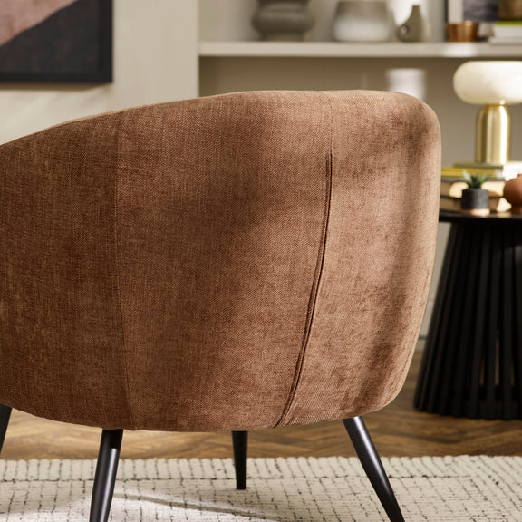 Brown upholstered chair in a room with a shelf and decor items.