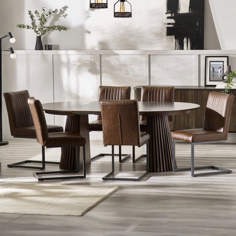 Dining room with a round wooden table and brown chairs in a modern interior setting.