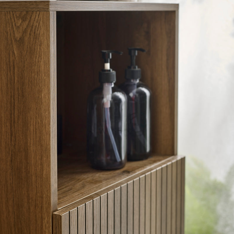 Two clear bottles with black pumps inside a wooden cabinet.