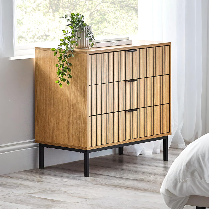 Wooden dresser with black legs in a room with a window and plant