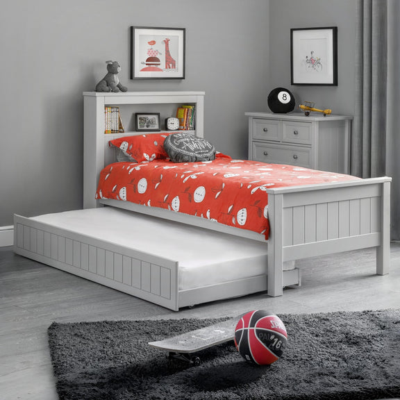Children's bedroom with a white bed, red blanket, and toys on a gray rug.
