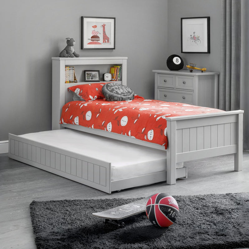 Children's bedroom with a white bed, red blanket, and toys on a gray rug.
