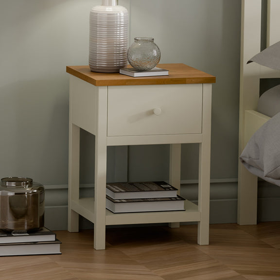 White nightstand with wooden top in a bedroom setting