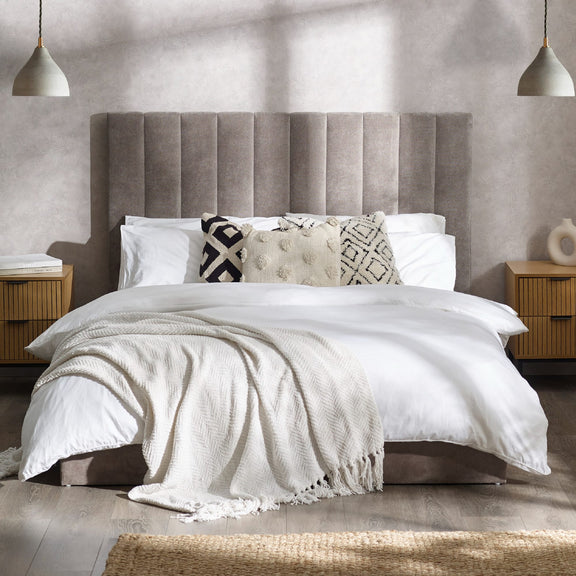 Neatly made bed with white bedding and decorative pillows in a bedroom setting.