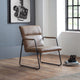 Brown leather chair in a room with a window and framed picture on the wall.