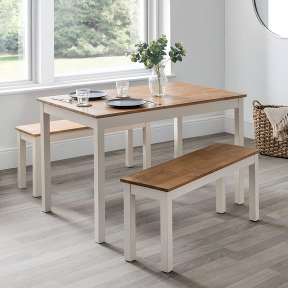 Dining table set with benches in a room with large windows.