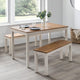 Dining table set with benches in a room with large windows.