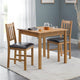 Wooden dining table with chairs in a room with a gray wall and white curtains.