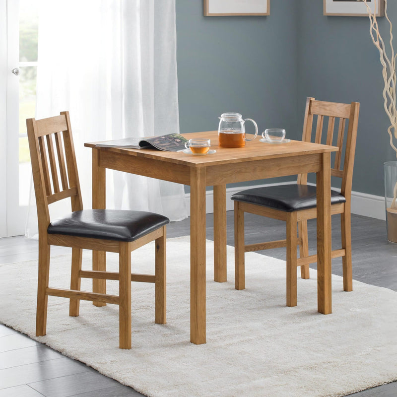 Wooden dining table with chairs in a room with a gray wall and white curtains.