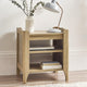 Wooden side table with books, a lamp, and a vase on a neutral background
