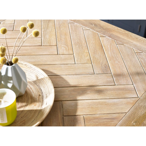 Wooden deck with herringbone pattern, a vase with yellow flowers, and a candle on a table.