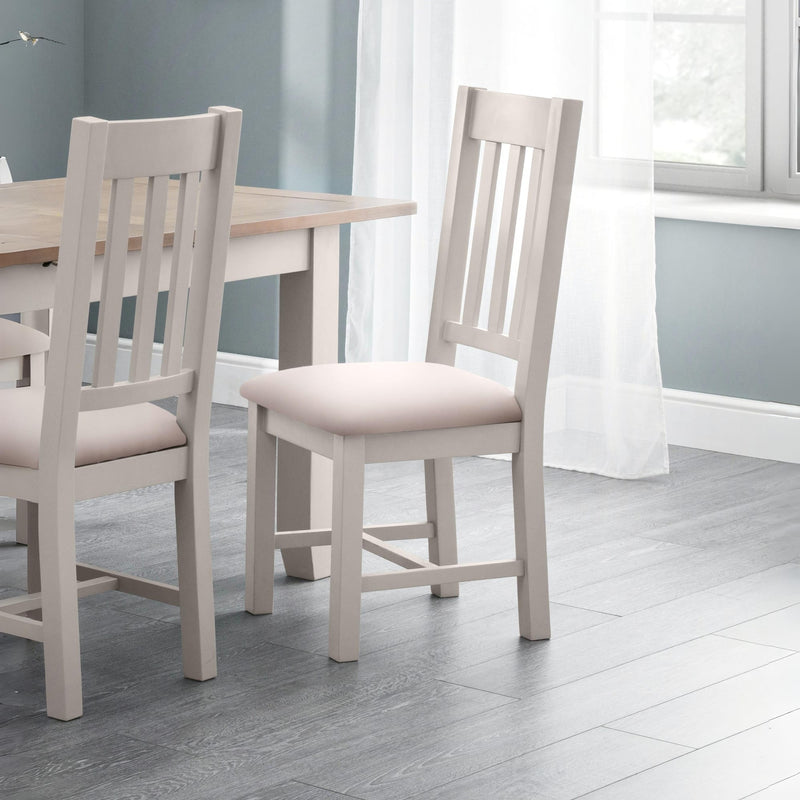 Dining table with two chairs in a room with light gray walls and wooden flooring.