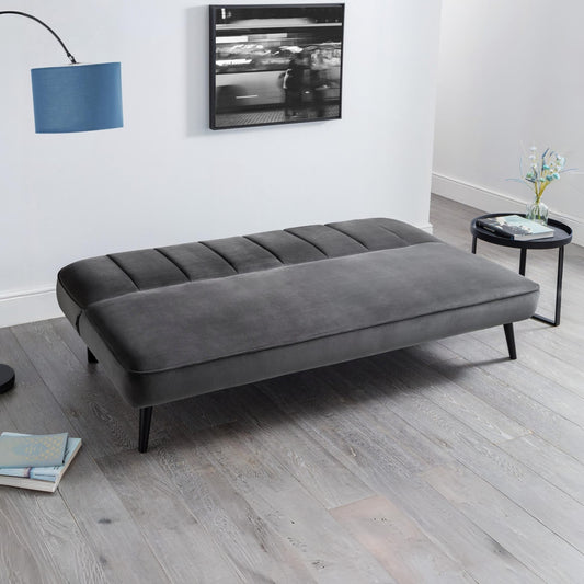 Gray sofa bed in a room with a TV and small table.