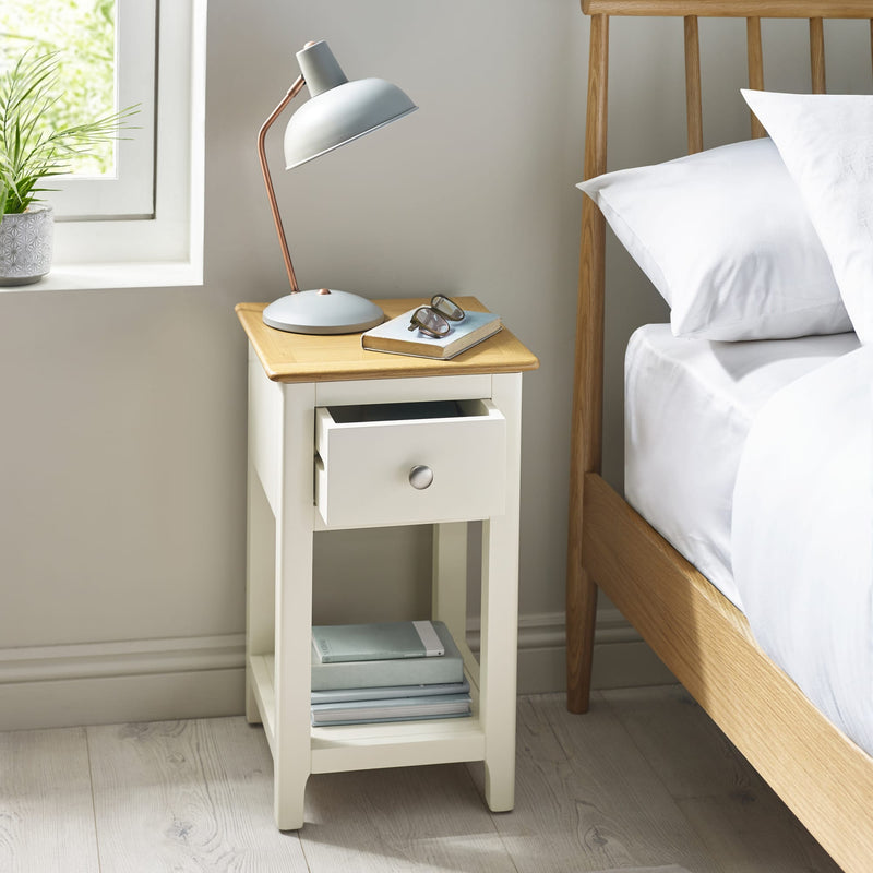 White nightstand with a lamp next to a bed in a bedroom