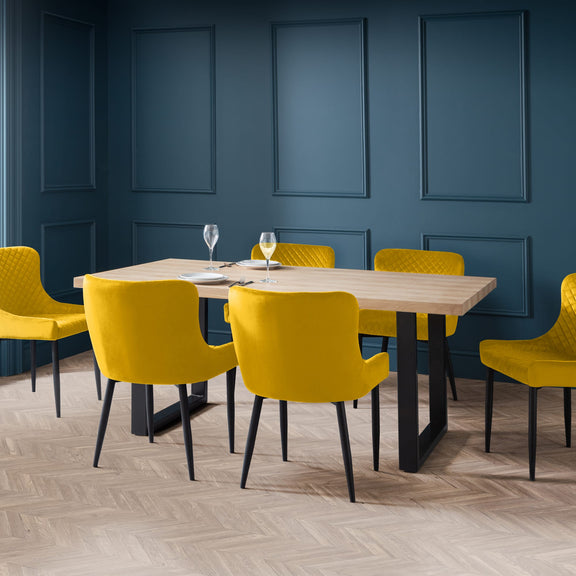 Dining room with a wooden table and yellow chairs against a blue paneled wall.