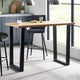 Dining table with black legs and a wooden top in a modern kitchen setting.