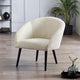 Cream-colored armchair with black legs in a room with a plant and decorative items.