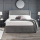 Gray upholstered bed with white bedding in a room with gray walls and wooden flooring.