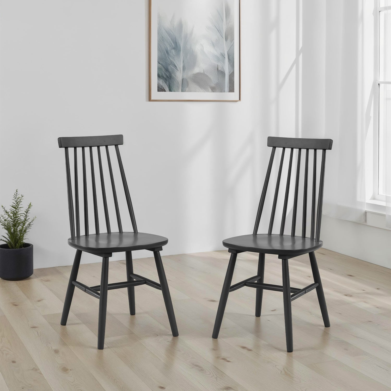 Two black wooden chairs in a room with a plant and abstract art on the wall.