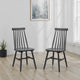 Two black wooden chairs in a room with a plant and abstract art on the wall.