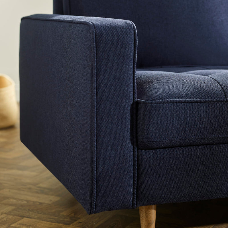 Navy blue upholstered chair with wooden legs on a wooden floor.