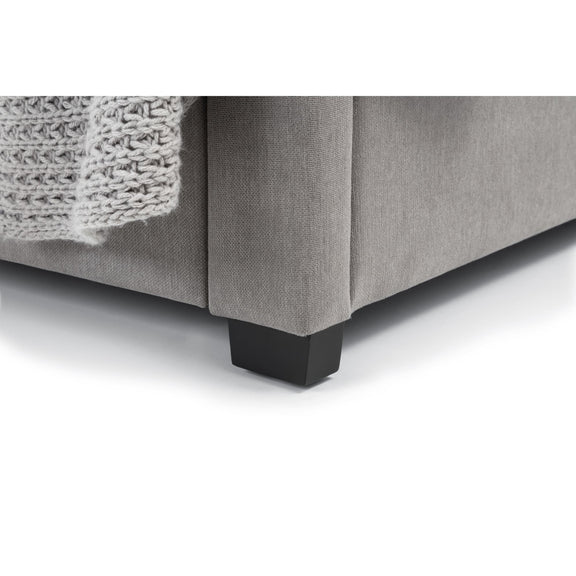Gray upholstered bed with dark wooden feet on a white background