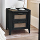 Black wooden bedside table with rattan drawer fronts beside bed