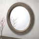 Decorative round mirror with intricate design on a plain wall.