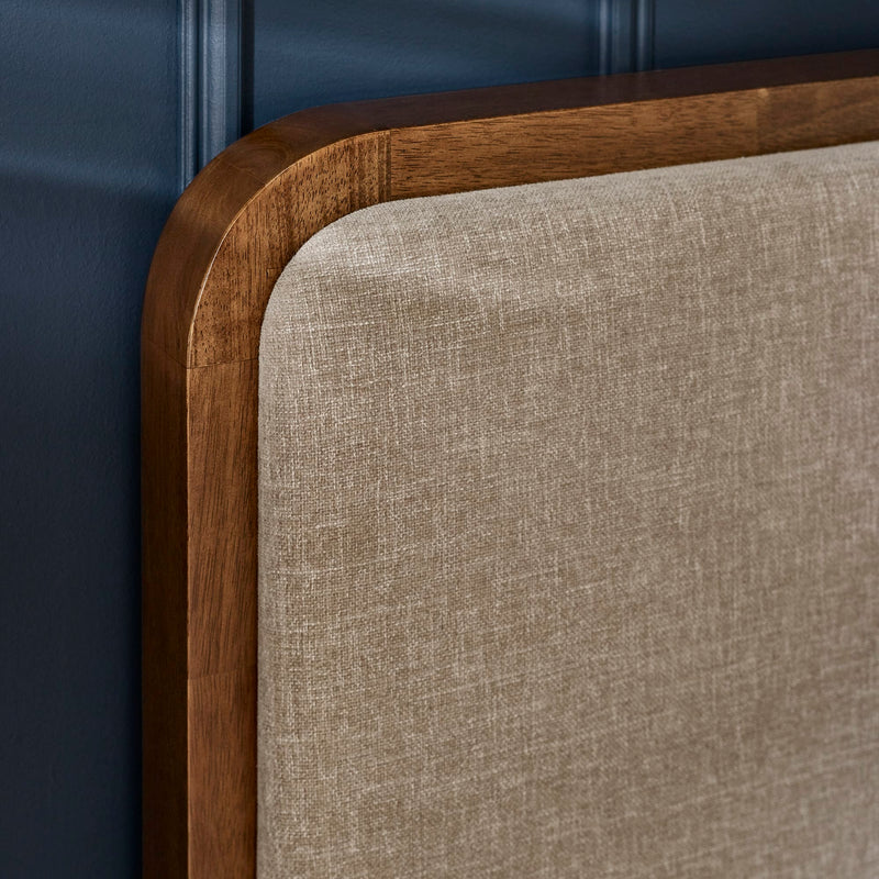 Close-up of a wooden headboard with beige upholstered panel against a blue wall.