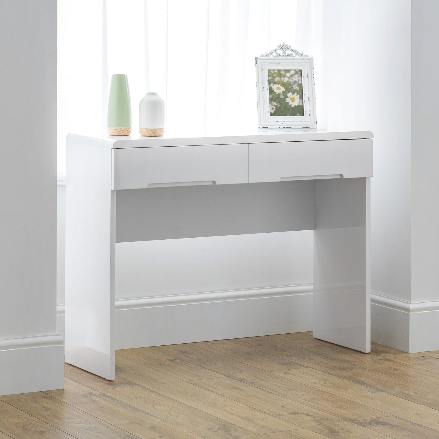 White console table with two drawers and a small mirror on a wooden floor.