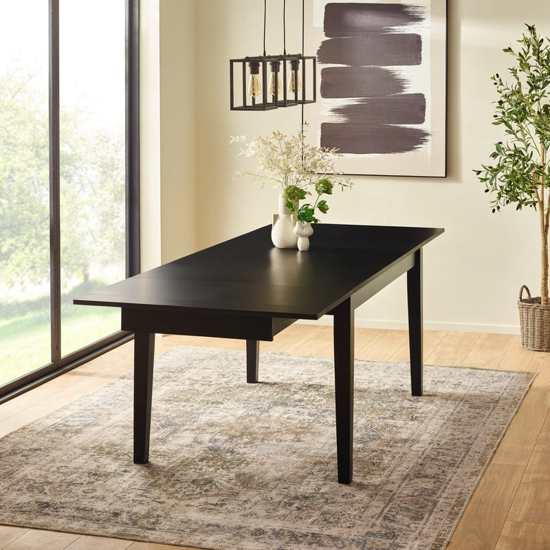 Black dining table in a room with a large window, rug, and abstract art on the wall.