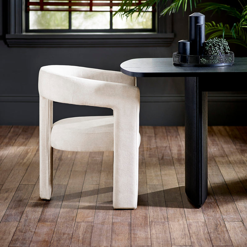 Beige chair and black dining table in a room with wooden flooring and a window in the background.