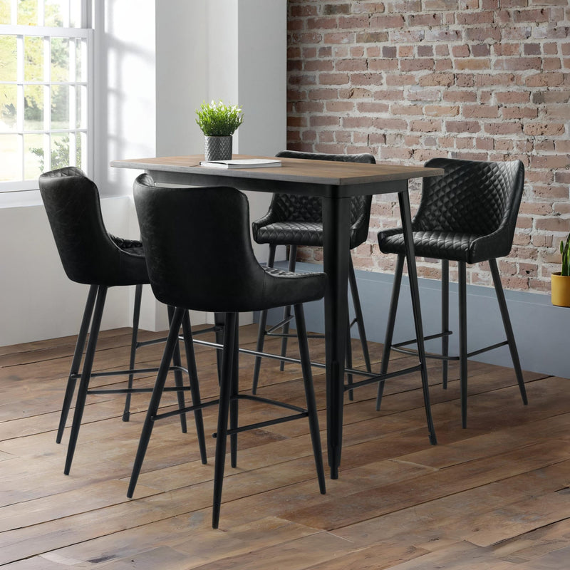 High table with black chairs in a room with brick wall and window
