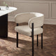 Beige chair with black legs on a wooden floor in a room with a neutral color scheme.