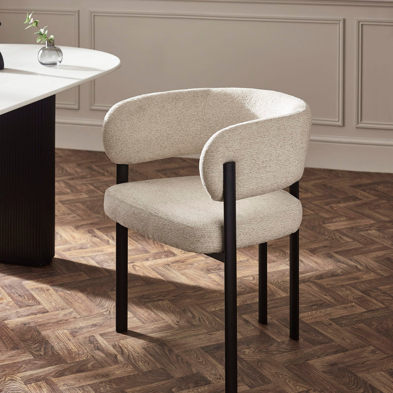 Beige chair with black legs on a wooden floor in a room with a neutral color scheme.