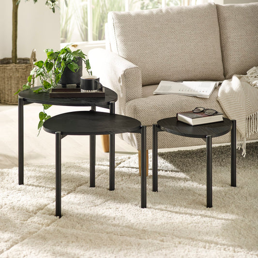 Set of three black nesting tables in a living room setting with a sofa and decor items.